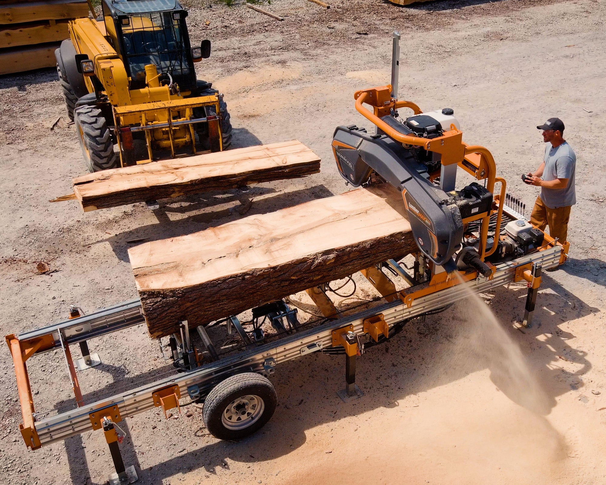 Worker operating a log splitter with logs on a wooden platform